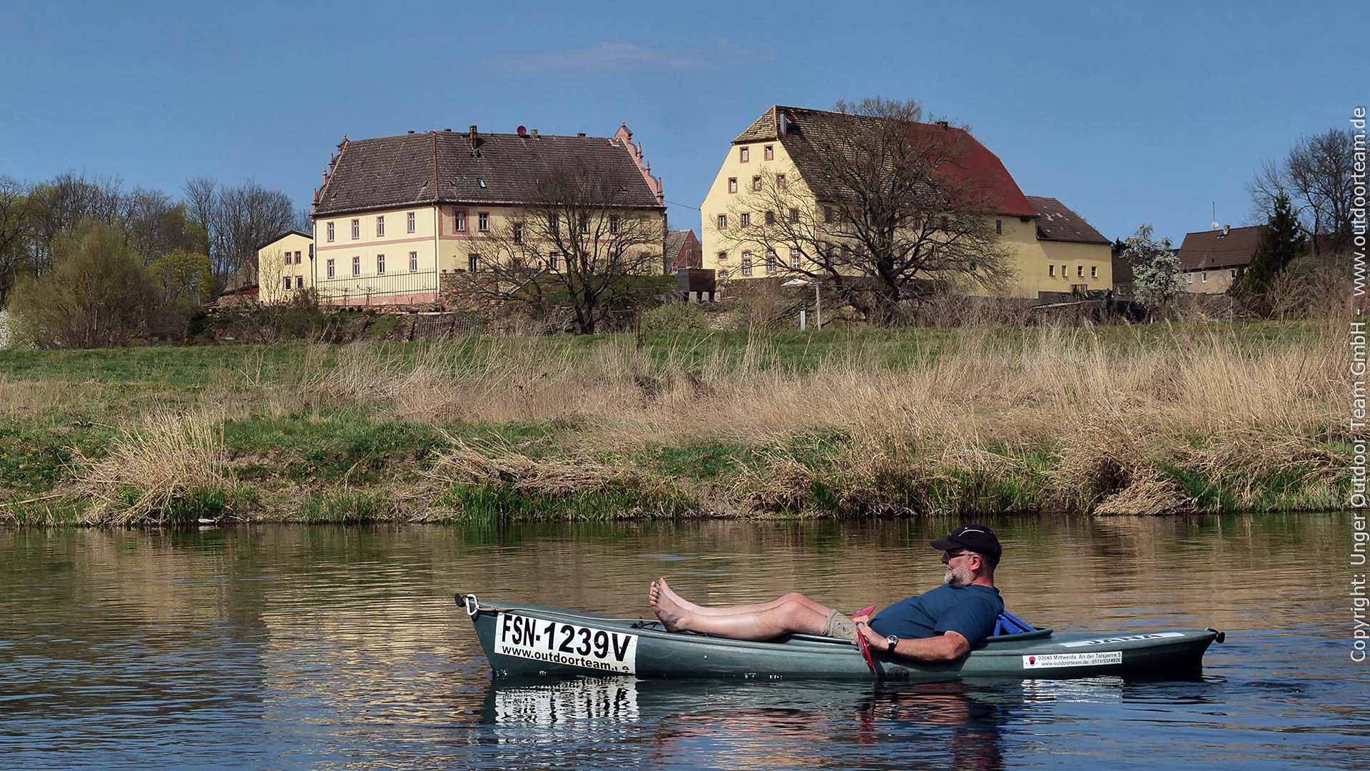tiefenentspannter, relaxter Kajakpaddler vor der Kulisse des restaurierten Rittergut Kössern