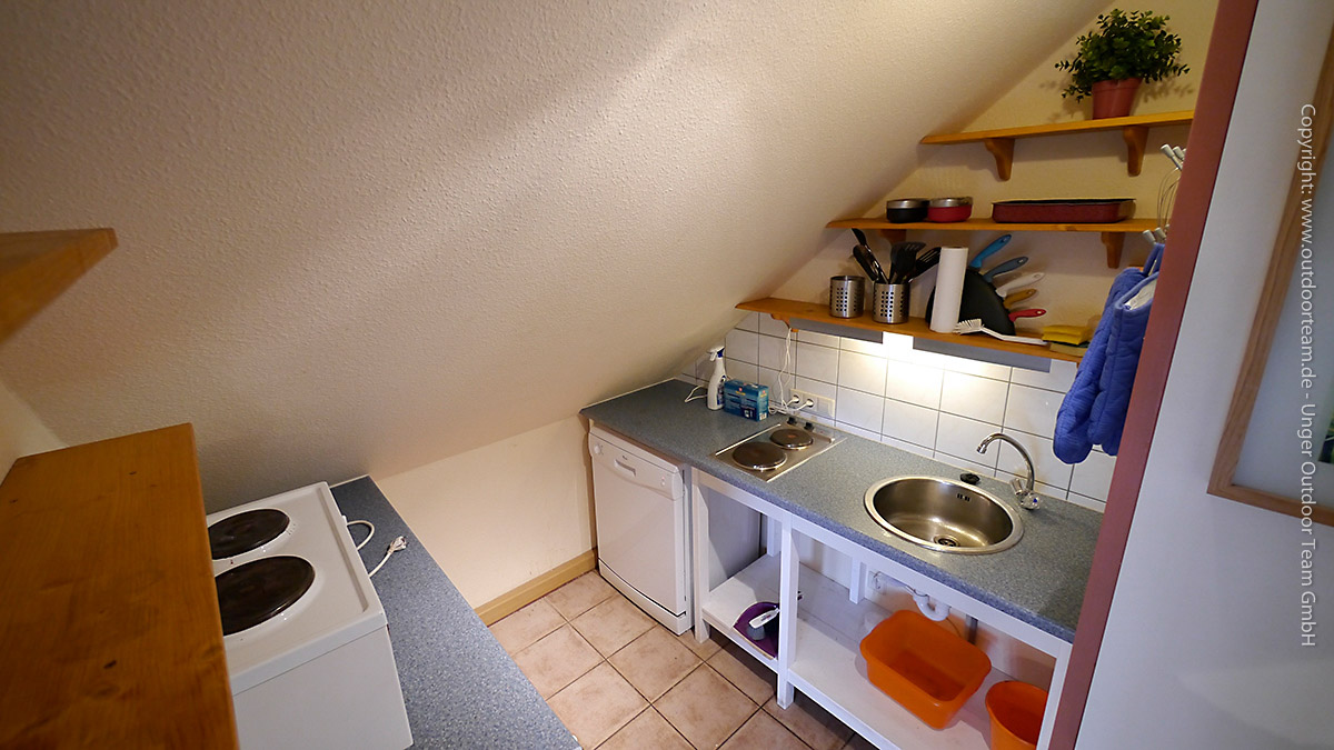 Küche mit kleinem Herd, Kühlschrank, Aufwaschbereich und Geschirrspüler - Ferienwohnung Klosterbuch
