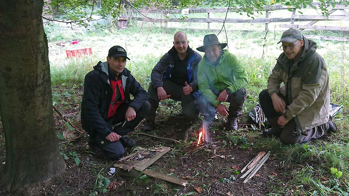 Kursteilnehmer vom Survival- und Wildniskurs beim Entfachen eines kleinen Kochfeuers - natürlich nur mit Zundermaterial und Feuerstahl.